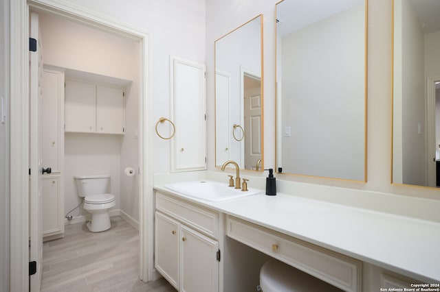 bathroom with hardwood / wood-style floors, vanity, and toilet