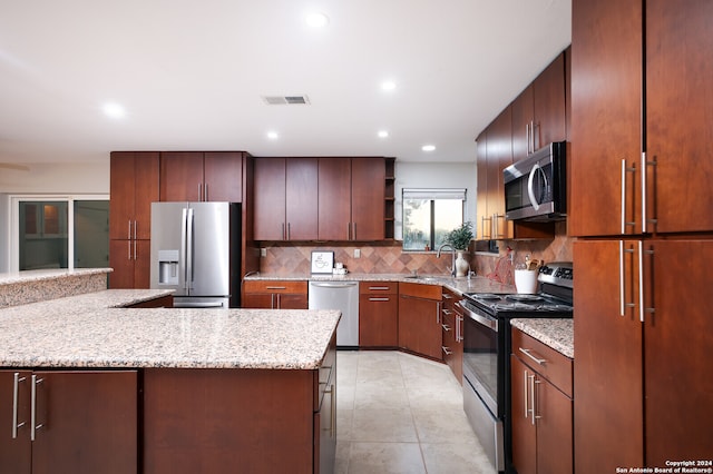 kitchen with light stone counters, backsplash, kitchen peninsula, light tile patterned flooring, and appliances with stainless steel finishes