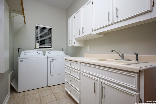 clothes washing area with cabinets, light tile patterned floors, sink, and washing machine and clothes dryer