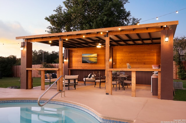 pool at dusk featuring outdoor lounge area, a patio, and an outdoor bar