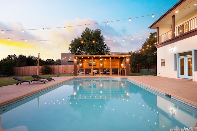 pool at dusk featuring a patio area