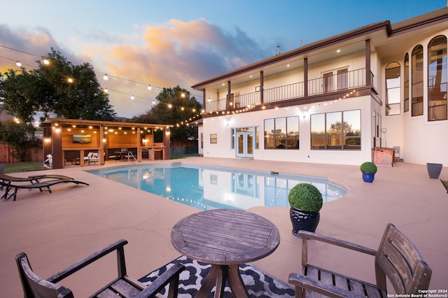 pool at dusk with a patio and french doors