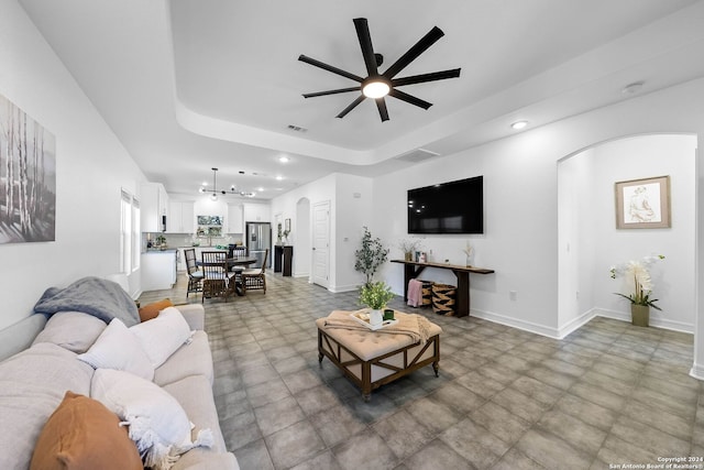 living room with ceiling fan and a raised ceiling