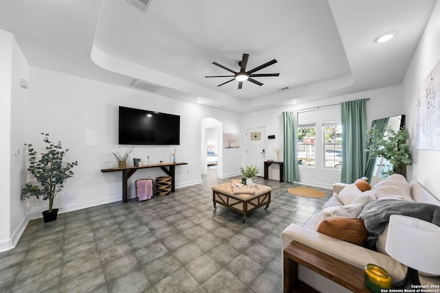 living room with a raised ceiling and ceiling fan