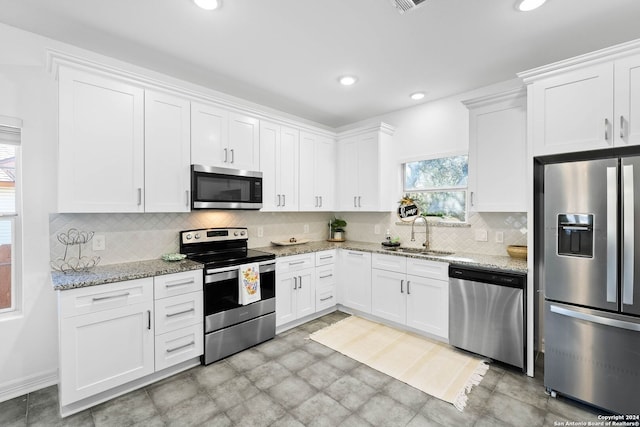 kitchen with light stone countertops, sink, tasteful backsplash, white cabinets, and appliances with stainless steel finishes