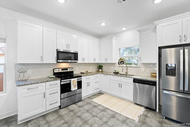 1153 Singing Hills Dr, Canyon Lake, TX 78133 - kitchen with appliances with stainless steel finishes, a sink, light stone counters, white cabinetry, and decorative backsplash