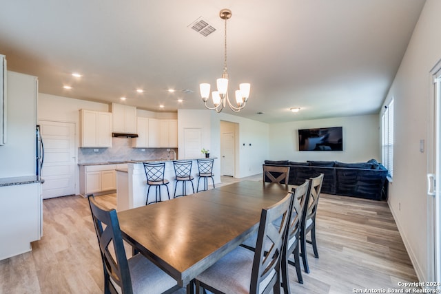 dining space with a chandelier and light hardwood / wood-style flooring