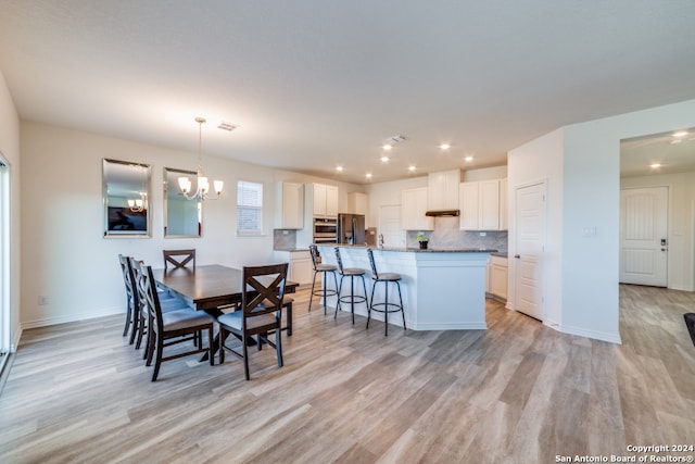 dining space with an inviting chandelier and light hardwood / wood-style floors