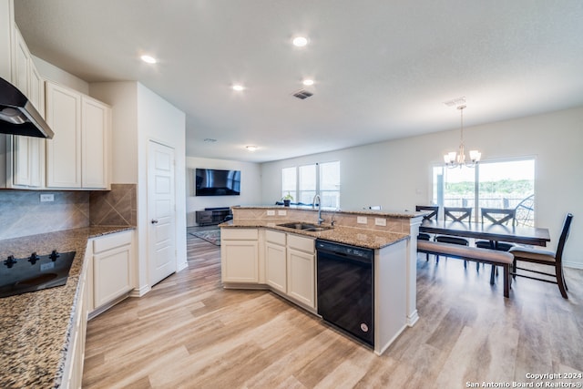 kitchen featuring decorative light fixtures, sink, white cabinets, black appliances, and a center island with sink