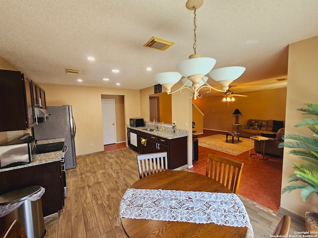 dining room with ceiling fan, sink, light hardwood / wood-style floors, and a textured ceiling