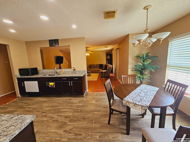 kitchen with ceiling fan with notable chandelier, pendant lighting, a textured ceiling, and sink