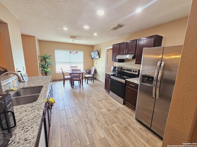 kitchen with light stone countertops, sink, light hardwood / wood-style floors, pendant lighting, and appliances with stainless steel finishes