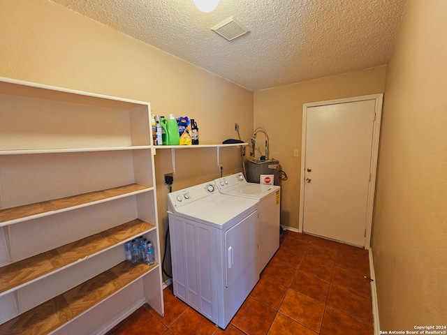 laundry room featuring electric water heater, separate washer and dryer, a textured ceiling, and dark tile patterned flooring