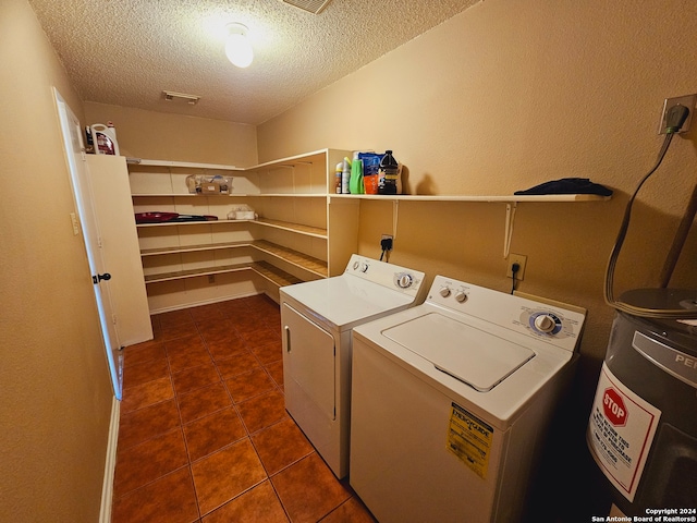 clothes washing area with washer and clothes dryer, dark tile patterned floors, and a textured ceiling