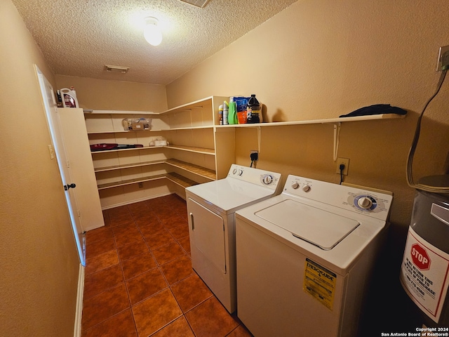 clothes washing area featuring separate washer and dryer, dark tile patterned flooring, and a textured ceiling