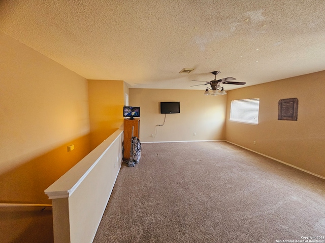 spare room featuring carpet flooring, ceiling fan, and a textured ceiling