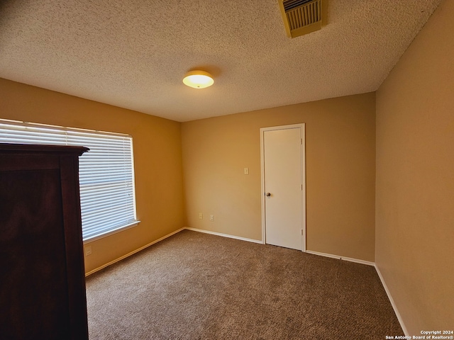 carpeted spare room with a textured ceiling