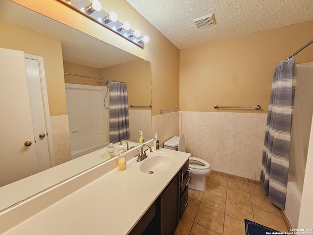 bathroom featuring vanity, tile patterned floors, toilet, tile walls, and a textured ceiling