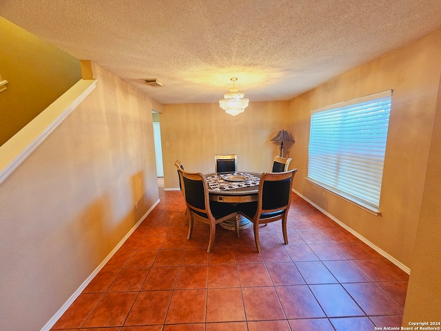 tiled dining area with a chandelier and a textured ceiling