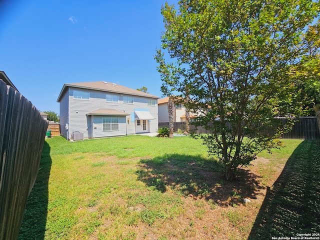 back of property with a yard and central AC