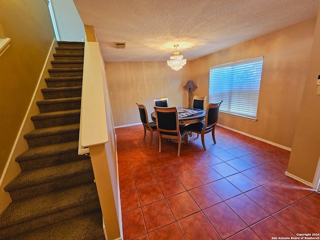 dining area featuring tile patterned flooring, a notable chandelier, and a textured ceiling