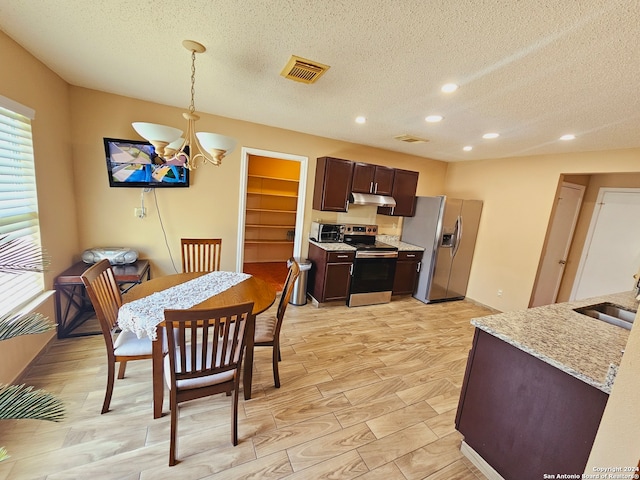 kitchen featuring appliances with stainless steel finishes, light hardwood / wood-style floors, an inviting chandelier, and hanging light fixtures