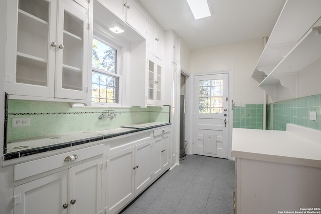 kitchen with backsplash, tile countertops, white cabinetry, and light tile patterned flooring