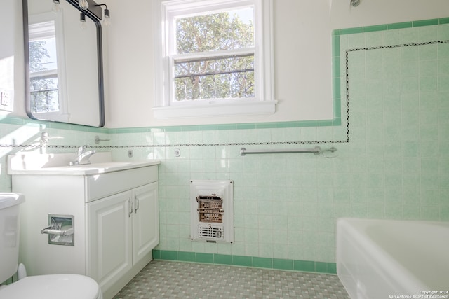 bathroom featuring vanity, tile patterned flooring, toilet, a tub to relax in, and tile walls