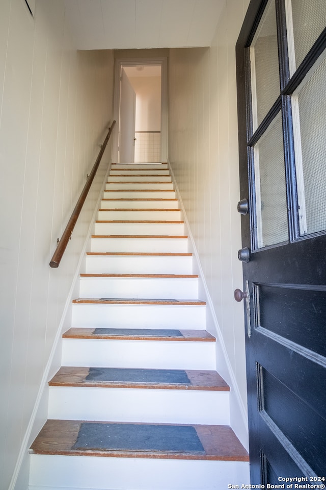 stairs featuring wood walls