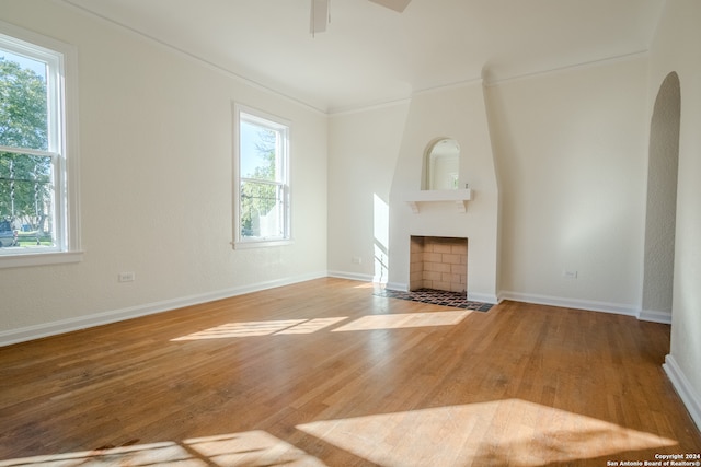 unfurnished living room with ceiling fan, light wood-type flooring, a fireplace, and ornamental molding