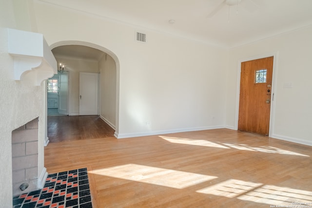 interior space with hardwood / wood-style flooring, ceiling fan, crown molding, and a tile fireplace