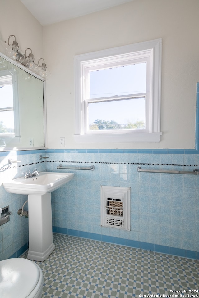 bathroom featuring heating unit, toilet, and tile walls