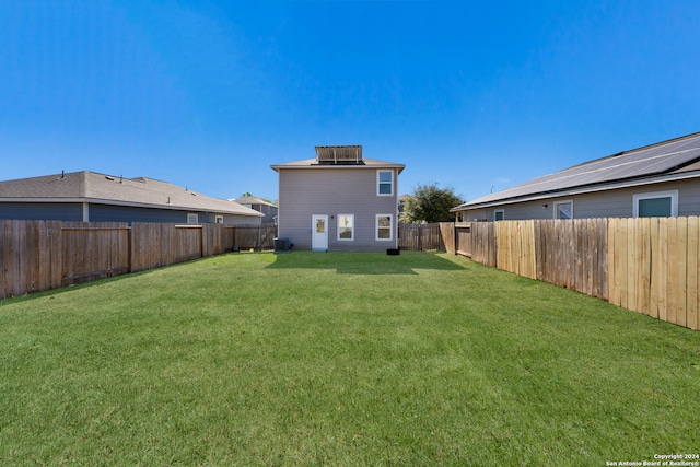 rear view of property featuring a yard and cooling unit