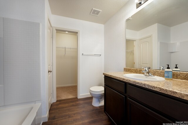 bathroom featuring hardwood / wood-style floors, vanity, toilet, and a washtub