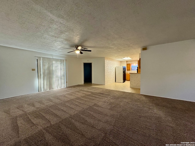 spare room featuring ceiling fan, light colored carpet, and a textured ceiling