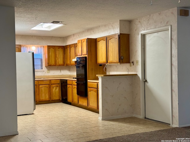 kitchen with double oven, a skylight, a textured ceiling, and fridge