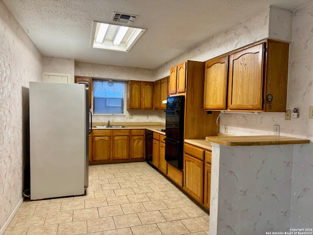 kitchen with black appliances, sink, and a textured ceiling