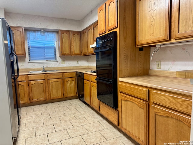 kitchen featuring a textured ceiling, sink, and black appliances