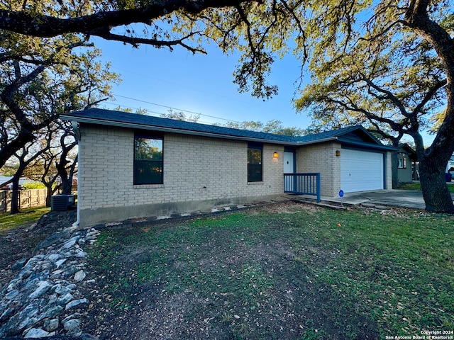 single story home featuring a front yard, a garage, and central AC unit