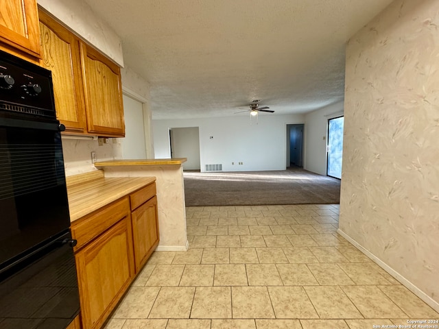 kitchen with kitchen peninsula, a textured ceiling, double oven, and ceiling fan