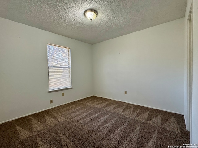 carpeted empty room featuring a textured ceiling