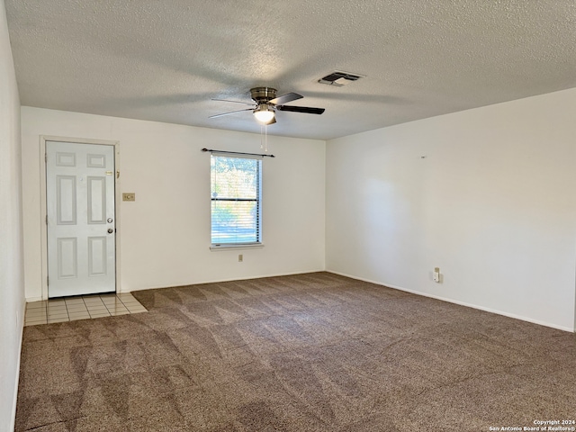 carpeted spare room featuring a textured ceiling and ceiling fan