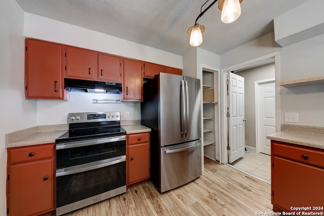 kitchen featuring light wood-type flooring, a textured ceiling, and appliances with stainless steel finishes