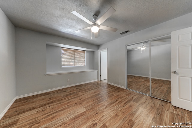 unfurnished bedroom featuring a closet, ceiling fan, hardwood / wood-style floors, and a textured ceiling