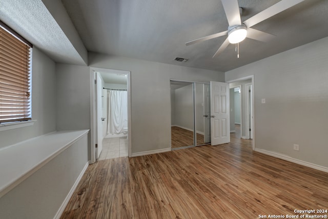 unfurnished bedroom with ensuite bath, ceiling fan, a closet, and light hardwood / wood-style floors