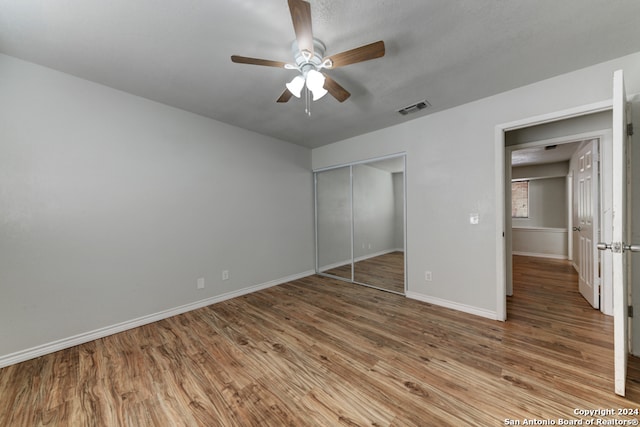 unfurnished bedroom featuring hardwood / wood-style floors, a closet, and ceiling fan