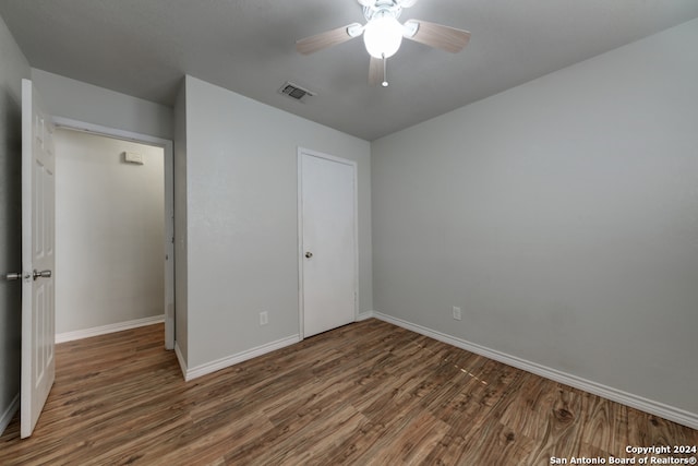 unfurnished bedroom with a closet, ceiling fan, and dark wood-type flooring