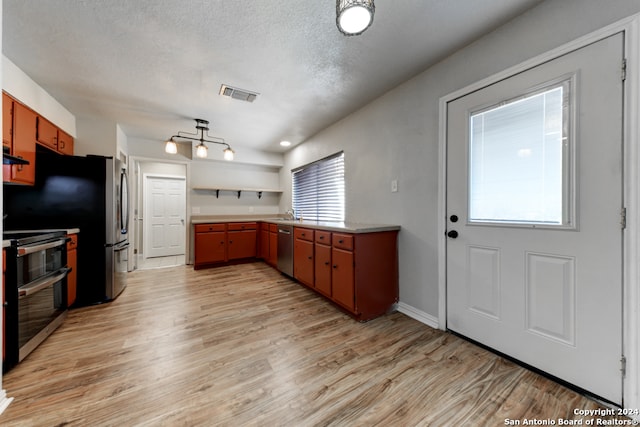 kitchen featuring stainless steel appliances, a textured ceiling, and light hardwood / wood-style floors