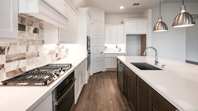 kitchen featuring sink, premium range hood, white cabinetry, hanging light fixtures, and stainless steel appliances