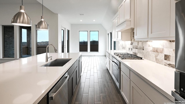 kitchen featuring appliances with stainless steel finishes, sink, pendant lighting, and white cabinets